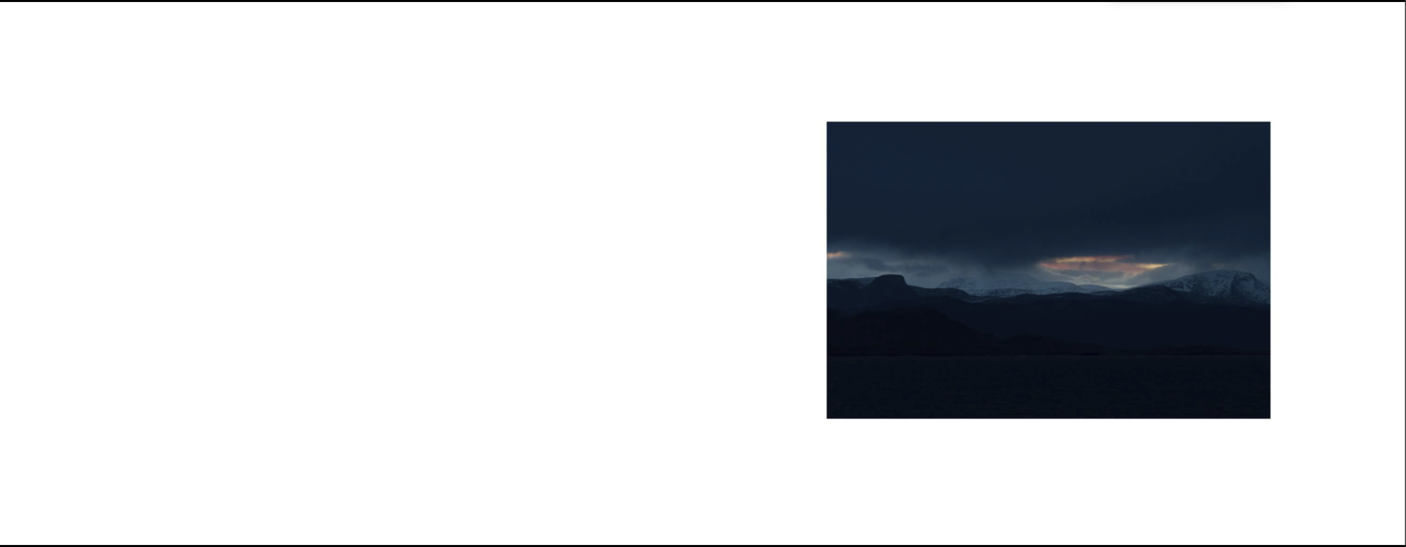 Dupla página com uma pequena fotografia de montanhas cobertas de neve sob um céu escuro, iluminadas por uma abertura no horizonte.